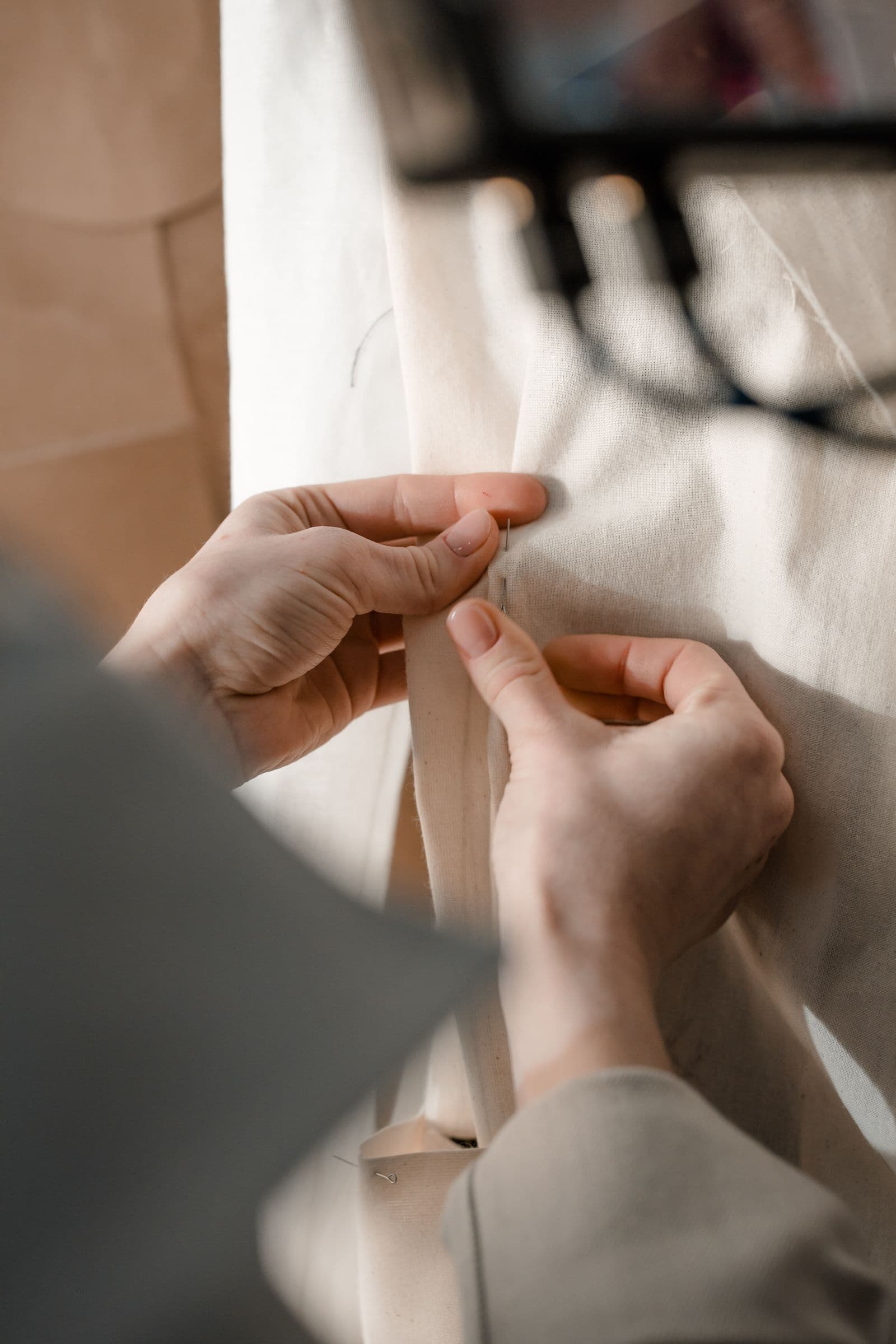 Hands pinning fabric during a tailoring fitting